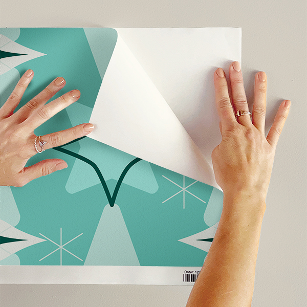 The artwork features a repeating geometric pattern of symmetrical shapes resembling elongated, curved diamonds or petals in various shades of blue and green. Each shape is split vertically with one half filled with a light blue and the other half filled with green or darker blue. The background is a light, almost pastel blue, which provides a soft yet vibrant backdrop. One of the blue shapes near the upper left contains a white starburst element, adding a focal point of brightness to the composition. The overall design conveys a modern, mid-century aesthetic with clean lines and harmonious color contrasts.